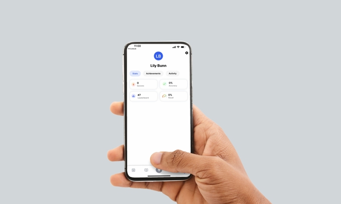 A hand holding a smartphone displaying a profile screen with the name "Lily Bunn;" showing sections for Goals, Achievements, and Activity.