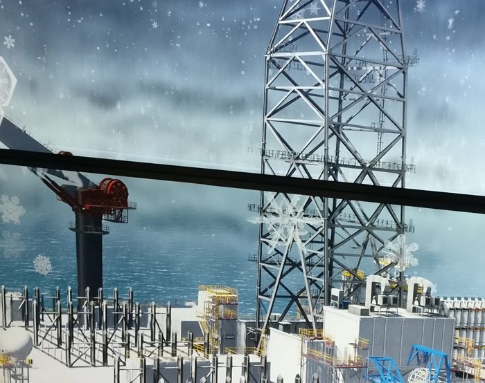 View of an offshore oil rig in the ocean, featuring a crane and various equipment on deck. Visible snowflakes suggest cold weather conditions.