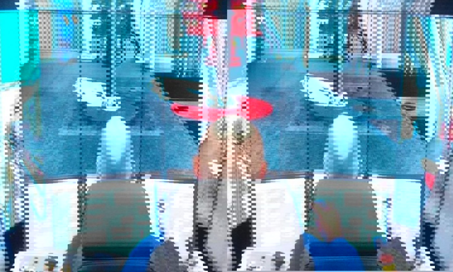 A person operates a control panel with multiple screens displaying an industrial setting, possibly a simulation or monitoring of machinery.