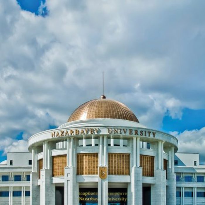 Facade of Nazarbayev University under a partly cloudy sky, featuring a prominent building with a golden dome and grand columns.