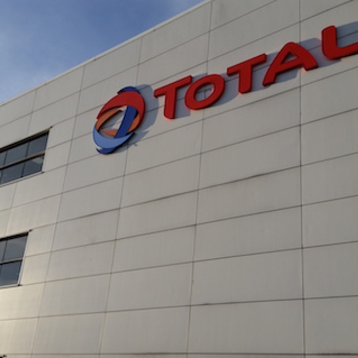 Exterior view of a white building with the Total logo prominently displayed on the upper side.